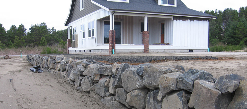 A house with a stone wall in front of it.